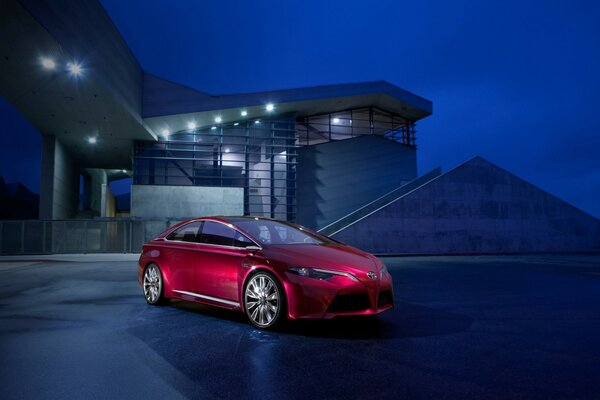 Coche rojo brillante en el fondo de la casa por la noche