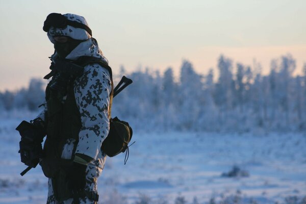 Hombre en camuflaje en el fondo del paisaje invernal