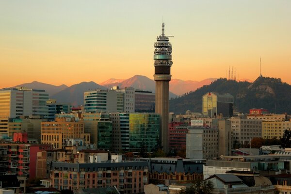 Una ciudad con una torre en el centro y montañas en el fondo