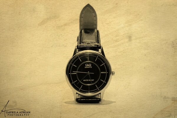 Reloj con esfera negra y correa sobre fondo claro