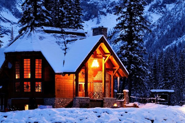 Cabaña en las montañas cubiertas de nieve del bosque de invierno