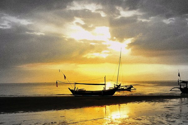 Imagen del mar con un barco en el fondo de la puesta de sol