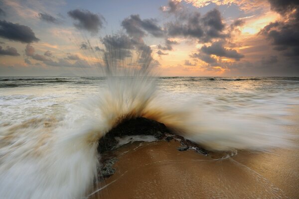 Atardecer. Playa de arena y olas de espuma