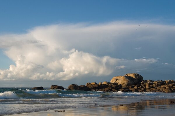 Olas en la playa de arena contra las nubes