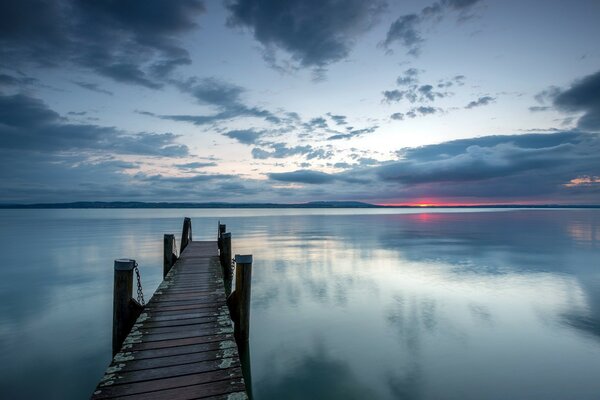 En el lago al atardecer se encuentra un estrecho puente