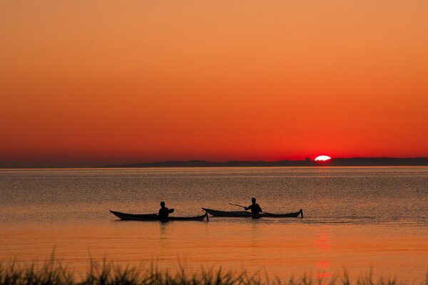 La gente navega en barcos durante la puesta del sol