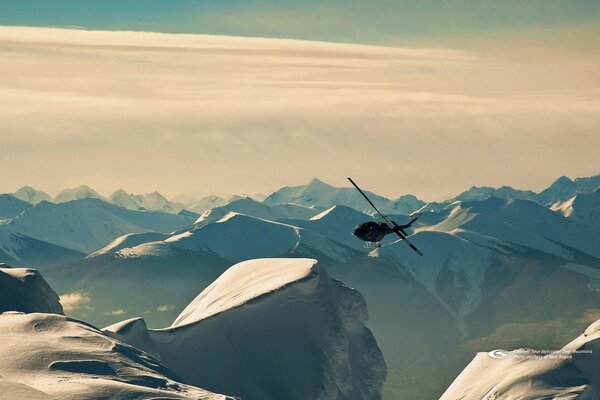 El helicóptero vuela entre los picos nevados de las montañas